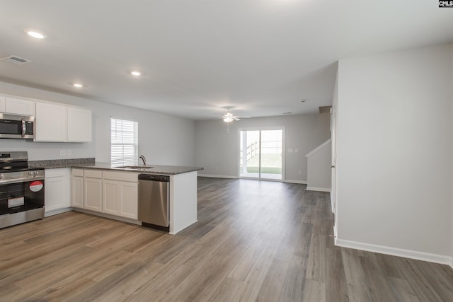 kitchen featuring kitchen peninsula, appliances with stainless steel finishes, sink, white cabinetry, and plenty of natural light