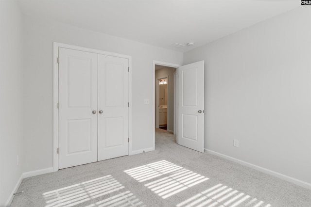 unfurnished bedroom featuring a closet and light colored carpet