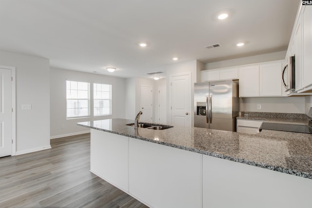 kitchen with white cabinetry, sink, stainless steel appliances, dark stone counters, and light hardwood / wood-style floors