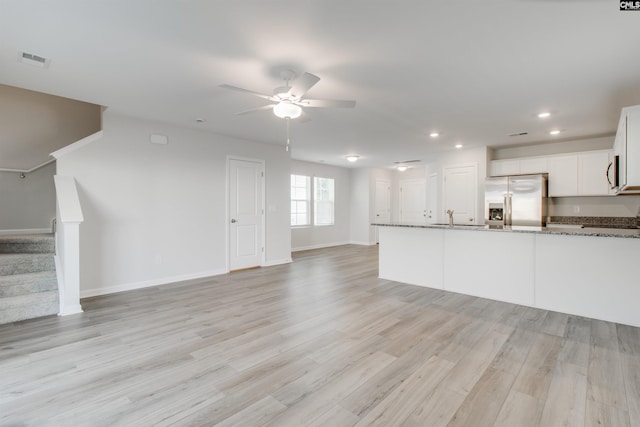 unfurnished living room with light hardwood / wood-style flooring, ceiling fan, and sink