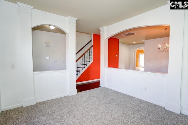 carpeted empty room featuring a notable chandelier