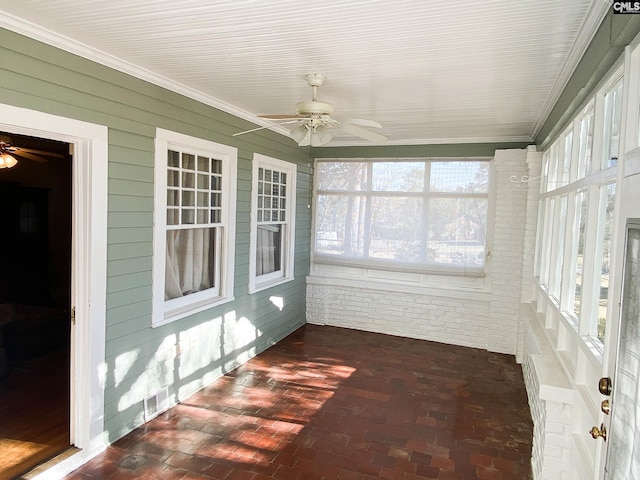 unfurnished sunroom featuring ceiling fan and a healthy amount of sunlight