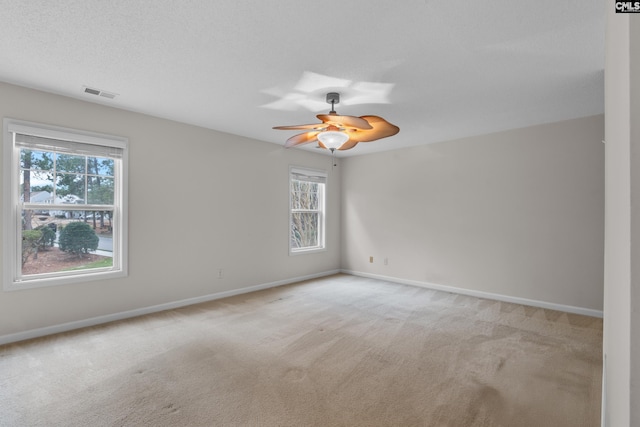 spare room featuring a wealth of natural light, ceiling fan, and light colored carpet