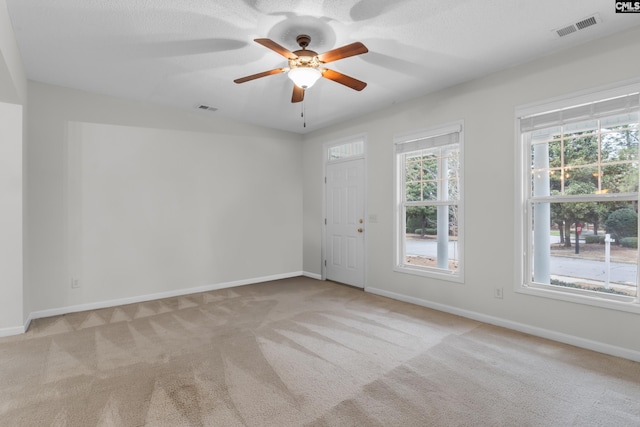 empty room featuring ceiling fan and light carpet