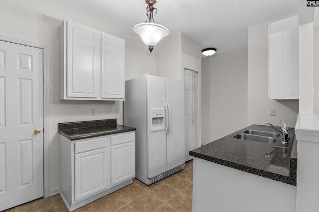 kitchen with sink, white fridge with ice dispenser, decorative light fixtures, light tile patterned flooring, and white cabinetry