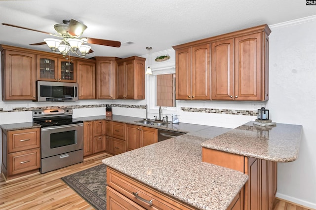 kitchen featuring tasteful backsplash, ornamental molding, stainless steel appliances, sink, and pendant lighting