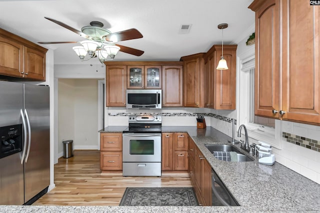 kitchen featuring dark stone counters, sink, ceiling fan, decorative light fixtures, and stainless steel appliances