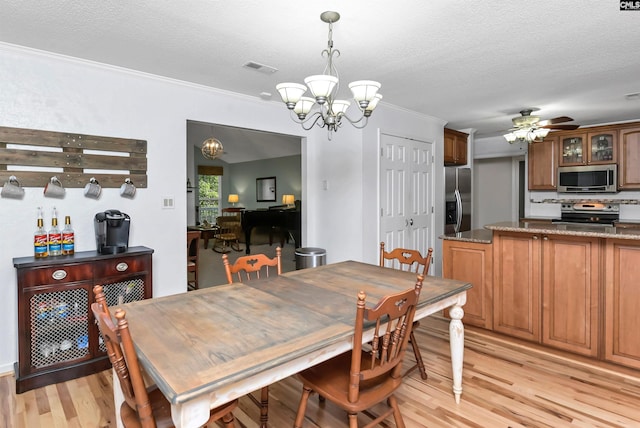 dining space with ceiling fan with notable chandelier, ornamental molding, a textured ceiling, and light hardwood / wood-style flooring