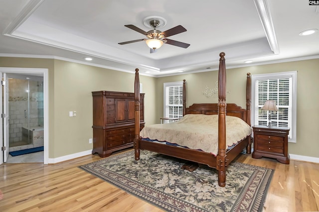 bedroom with ensuite bathroom, crown molding, ceiling fan, a tray ceiling, and light hardwood / wood-style floors