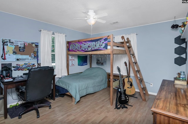 bedroom featuring ceiling fan, light wood-type flooring, and a textured ceiling