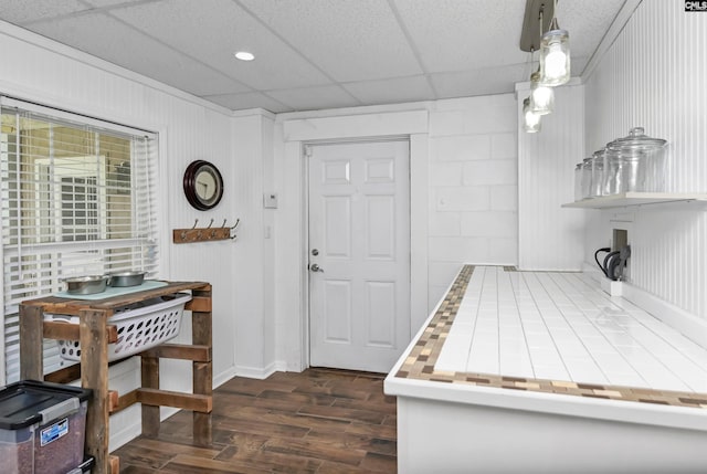 kitchen featuring dark hardwood / wood-style flooring, hanging light fixtures, and a paneled ceiling