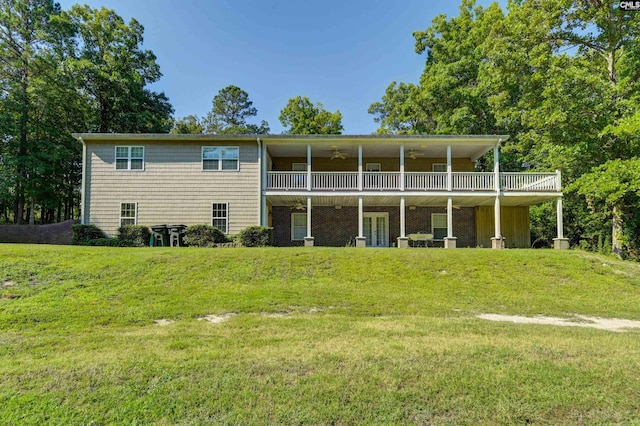 rear view of house with ceiling fan and a yard