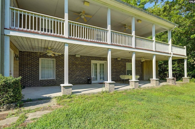 rear view of house featuring french doors, ceiling fan, a balcony, a yard, and a patio