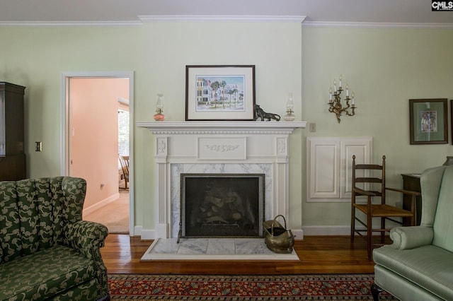 living area with a premium fireplace, crown molding, and hardwood / wood-style flooring