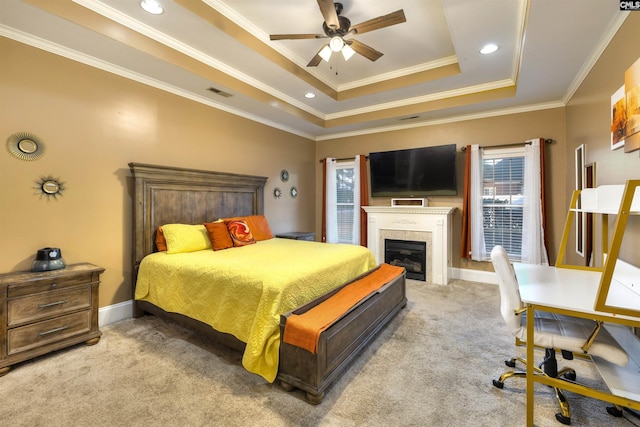 carpeted bedroom with a raised ceiling, ceiling fan, crown molding, and a tiled fireplace