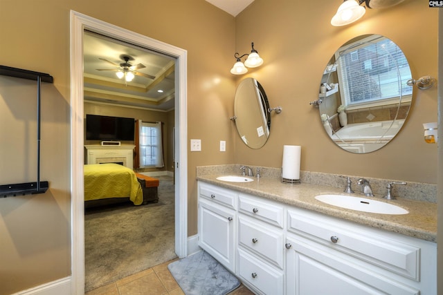 bathroom with ceiling fan, a raised ceiling, tile patterned floors, crown molding, and vanity