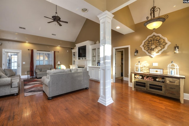 living room with decorative columns, ceiling fan, dark hardwood / wood-style flooring, and high vaulted ceiling