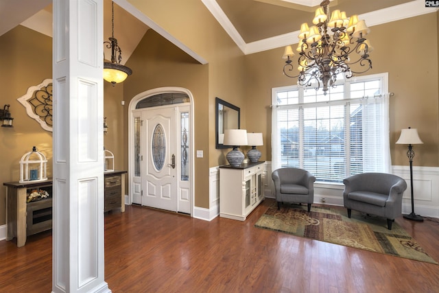 foyer featuring dark hardwood / wood-style flooring, ornate columns, vaulted ceiling, crown molding, and a chandelier