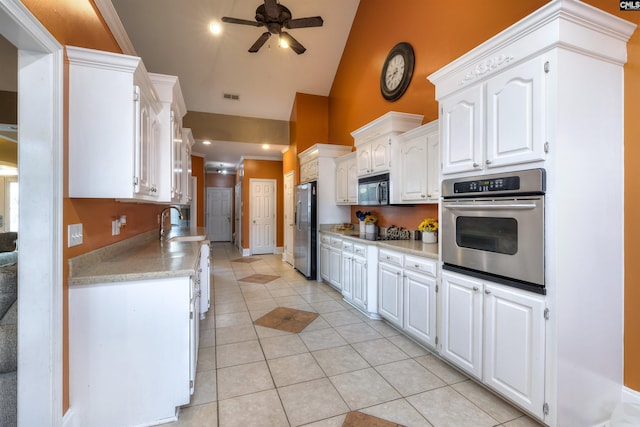 kitchen with black appliances, light tile patterned flooring, and white cabinets