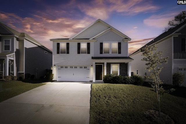 view of front facade featuring board and batten siding, a yard, driveway, and a garage