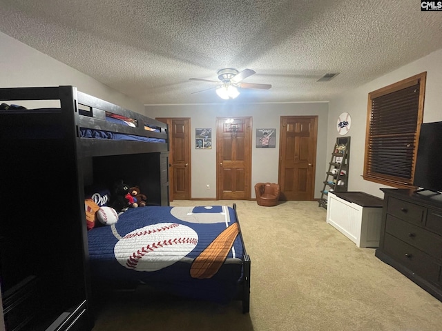 bedroom with a textured ceiling, ceiling fan, and light carpet