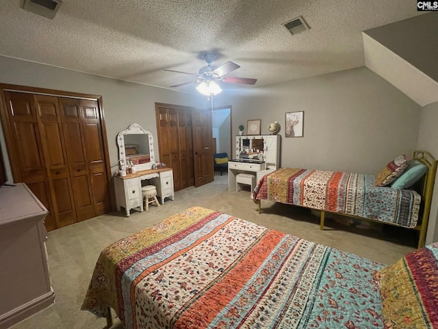 bedroom featuring lofted ceiling, two closets, ceiling fan, and light carpet