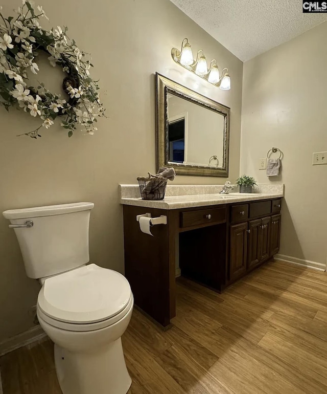 bathroom featuring toilet, wood-type flooring, vanity, and a textured ceiling