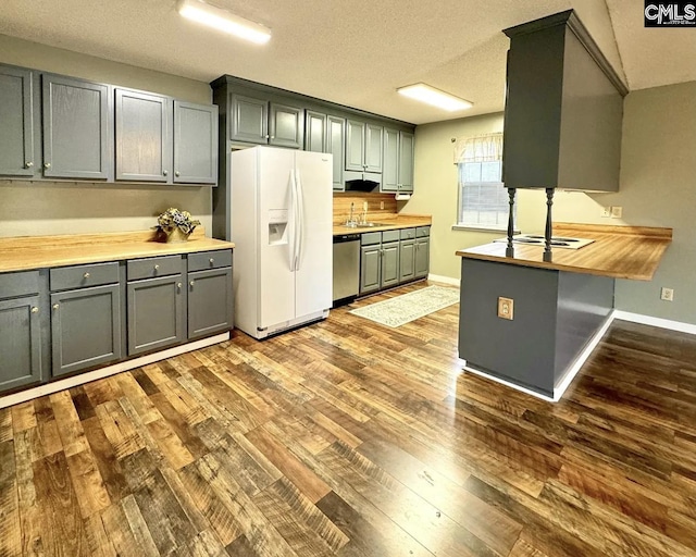 kitchen featuring hardwood / wood-style floors, white fridge with ice dispenser, dishwasher, a textured ceiling, and butcher block counters