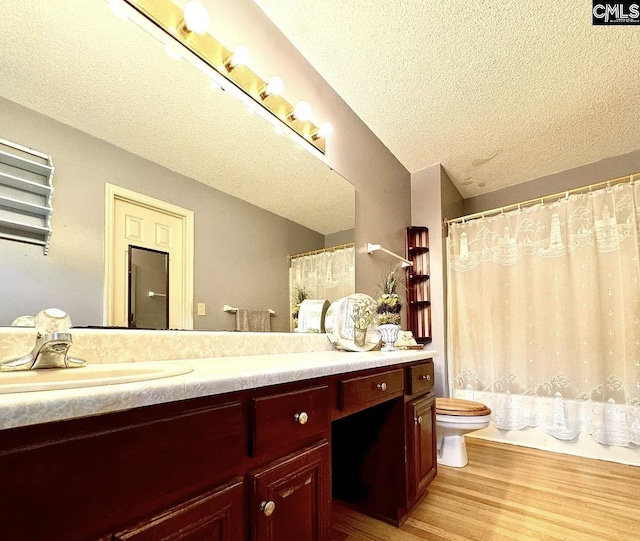 bathroom with a textured ceiling, hardwood / wood-style flooring, vanity, and toilet