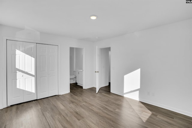 unfurnished bedroom with light hardwood / wood-style floors, ensuite bathroom, and a closet