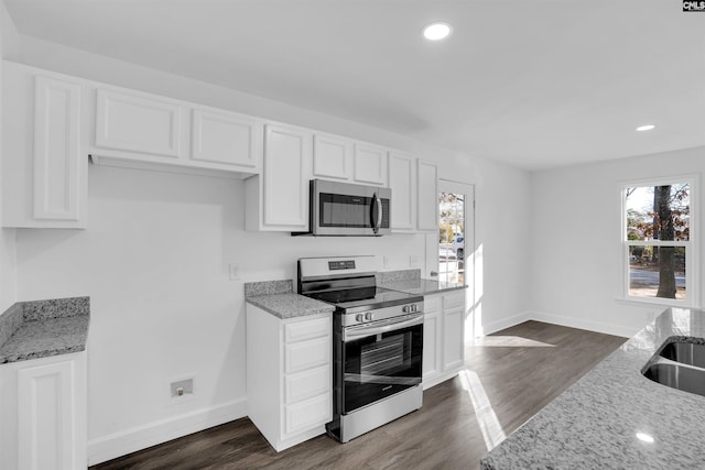 kitchen featuring appliances with stainless steel finishes, white cabinetry, dark hardwood / wood-style floors, and light stone countertops