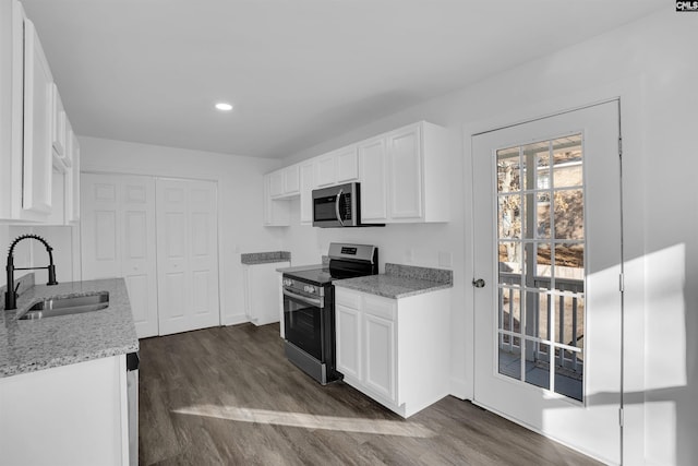 kitchen with stainless steel appliances, sink, white cabinetry, light stone countertops, and dark wood-type flooring