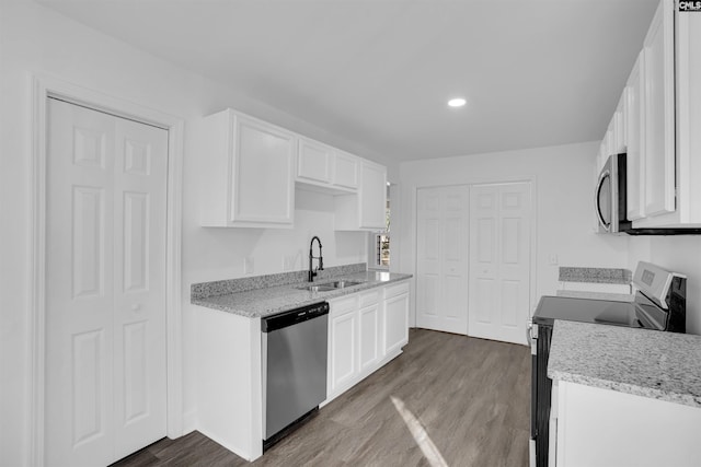 kitchen with light stone counters, stainless steel appliances, dark hardwood / wood-style flooring, white cabinets, and sink