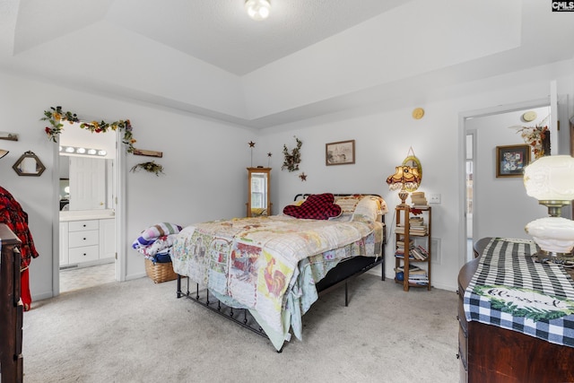 bedroom with connected bathroom, a tray ceiling, and light colored carpet