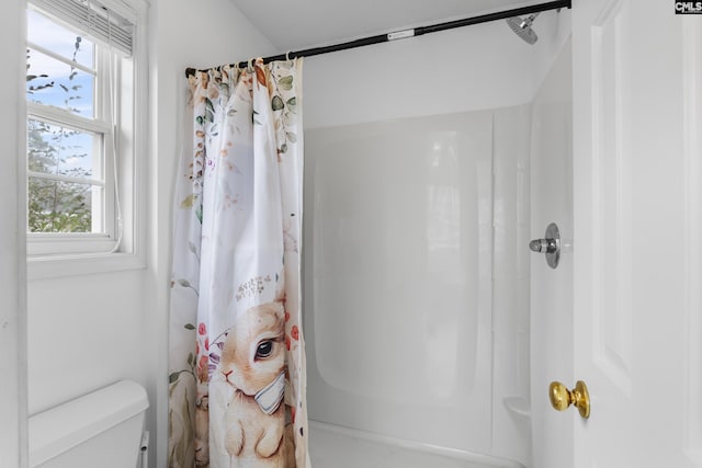 bathroom featuring a shower with shower curtain, a wealth of natural light, and toilet