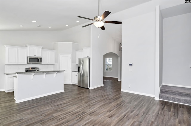 kitchen with a kitchen island, white cabinets, a kitchen bar, and appliances with stainless steel finishes