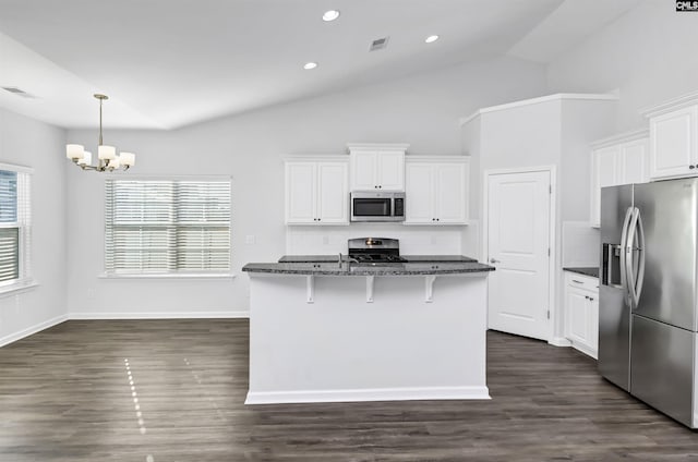 kitchen with stainless steel appliances, white cabinetry, dark stone countertops, decorative backsplash, and a center island with sink