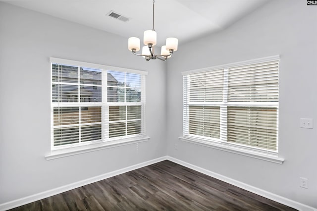 empty room with an inviting chandelier and dark wood-type flooring