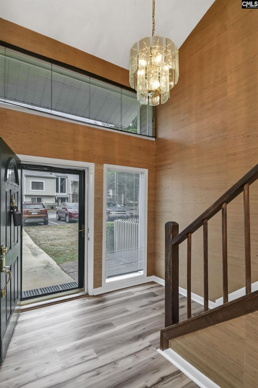 entryway with a high ceiling, a notable chandelier, and wood-type flooring