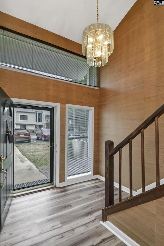 entryway with a high ceiling, a notable chandelier, and wood-type flooring