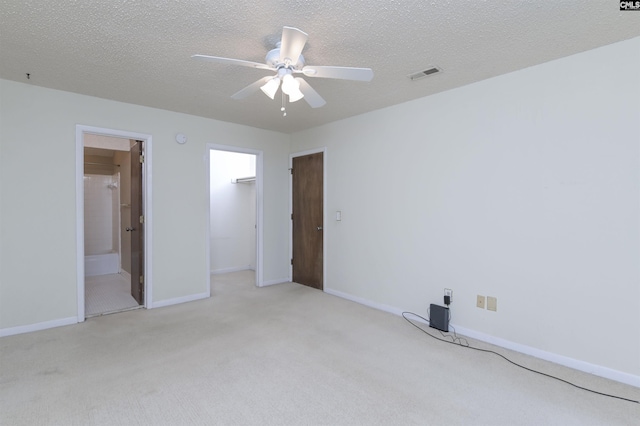 unfurnished bedroom with connected bathroom, a closet, light colored carpet, ceiling fan, and a textured ceiling