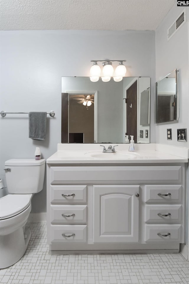 bathroom with a textured ceiling, tile patterned flooring, vanity, and toilet