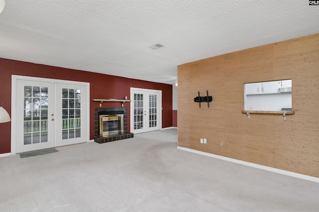 unfurnished living room with french doors, a textured ceiling, and light colored carpet