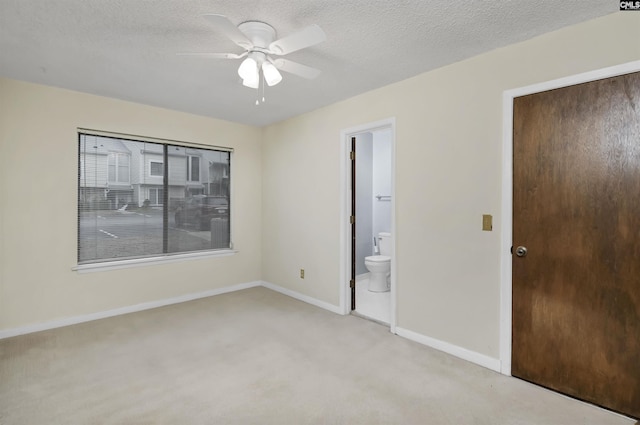 unfurnished bedroom featuring connected bathroom, a textured ceiling, ceiling fan, and light colored carpet