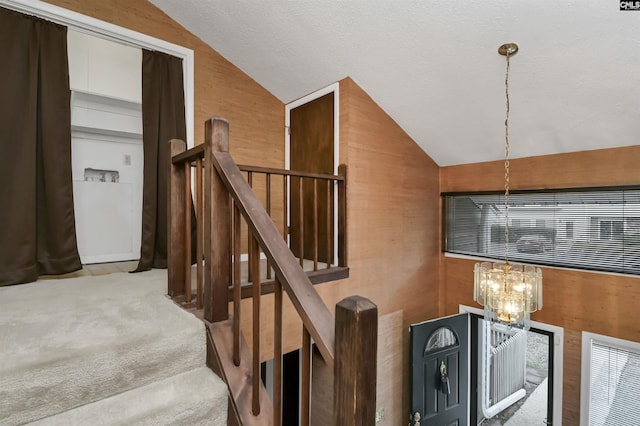 stairway featuring a notable chandelier, wood walls, lofted ceiling, and carpet