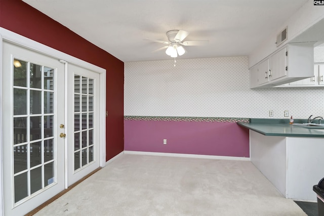 kitchen featuring light colored carpet, ceiling fan, french doors, sink, and white cabinetry