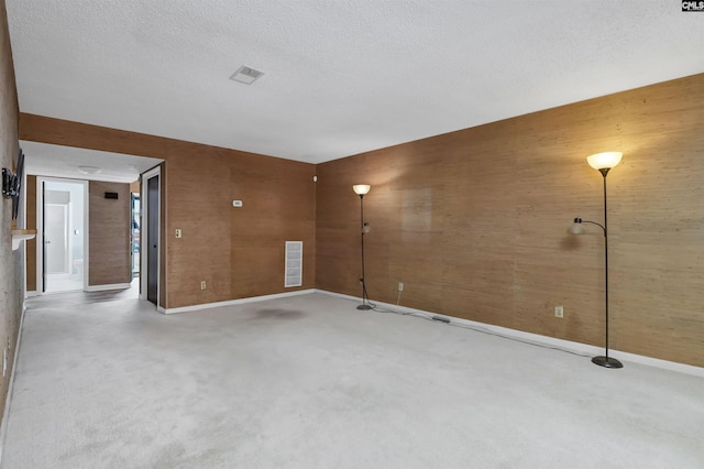 carpeted empty room with wood walls and a textured ceiling