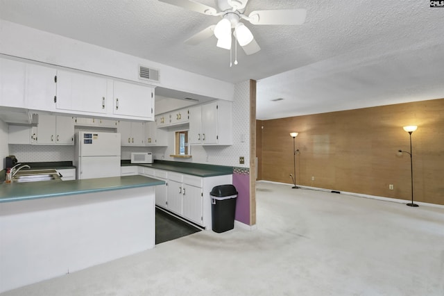 kitchen featuring white appliances, white cabinets, sink, and dark colored carpet