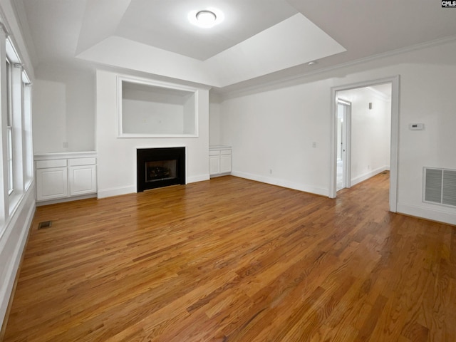 unfurnished living room featuring ornamental molding, hardwood / wood-style floors, and a raised ceiling