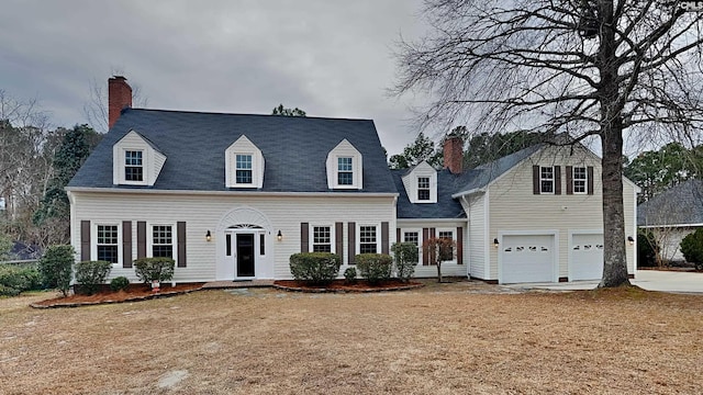 new england style home with a front yard and a garage